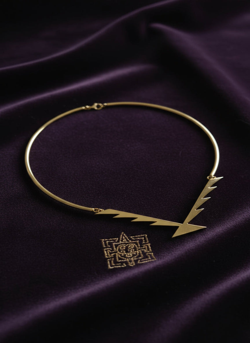 Gold necklace with a geometric pendant on a purple fabric background